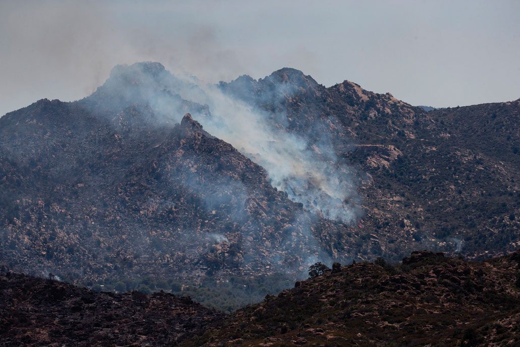 A photograph of smoke rising from the 2021 Telegraph Fire burning a mountainous landscape in Arizona